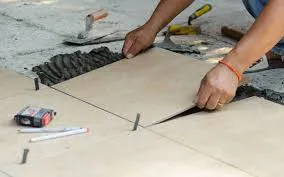Person installing large floor tiles, tools nearby.