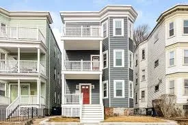 Three-story gray house with white balconies.