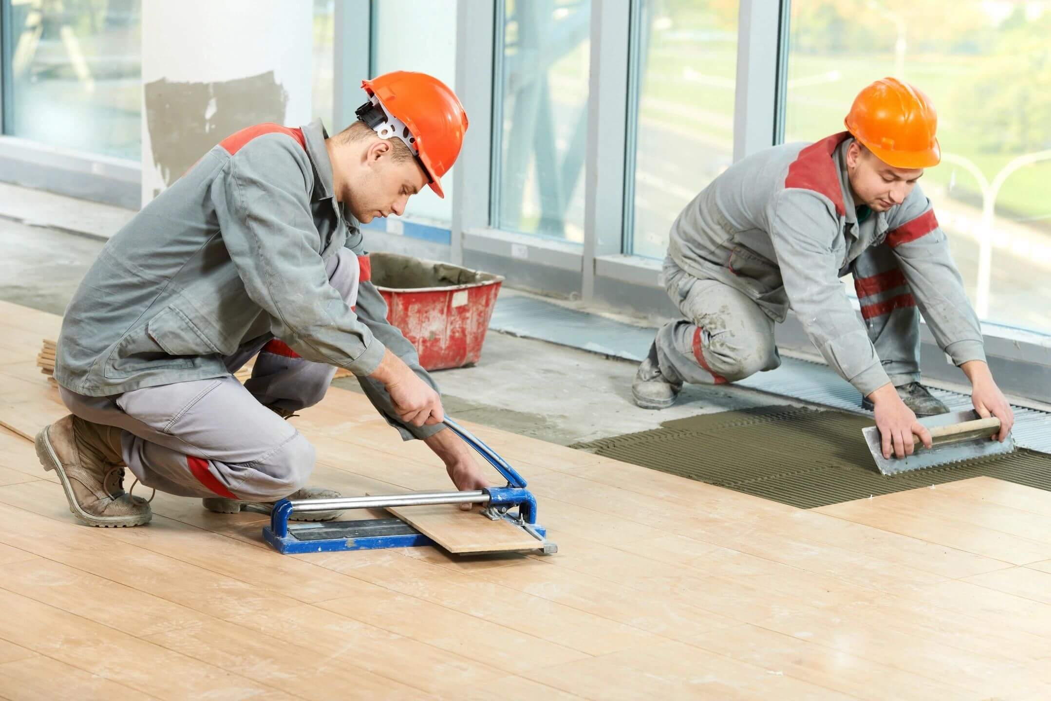 Workers installing tiles on a floor.