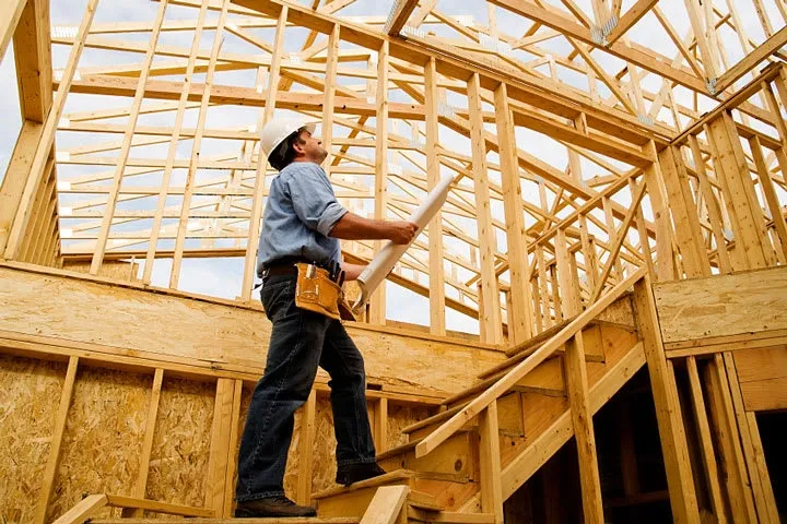 Builder inspecting wooden house framework construction.