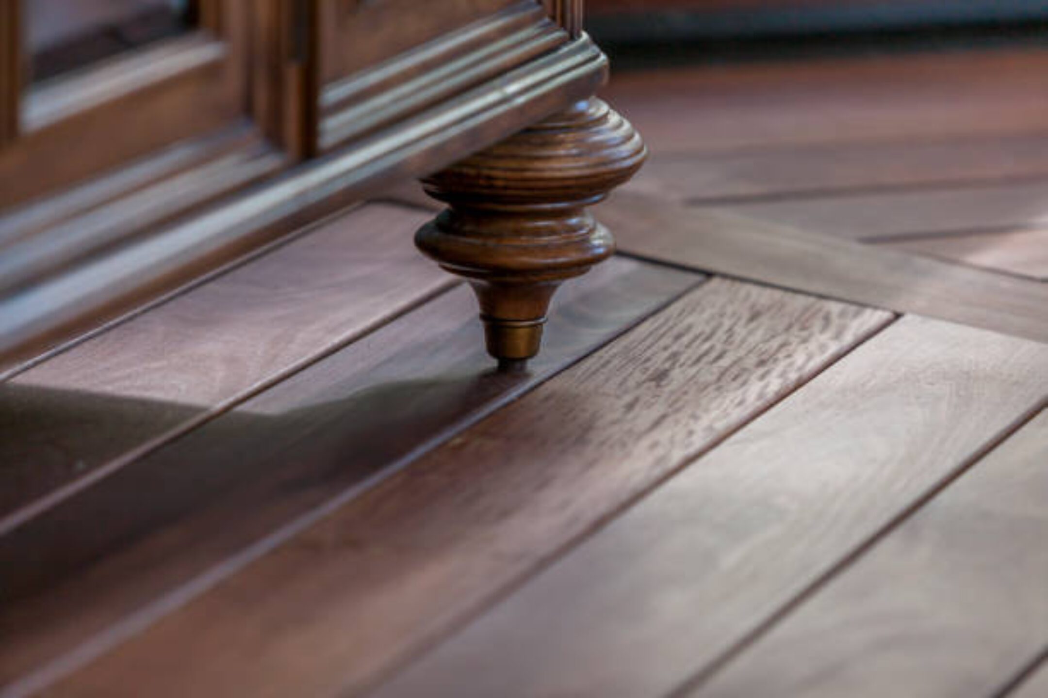Wooden furniture leg on polished wooden floor.